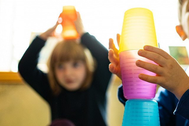 Kinder stapeln Becher in den Räumlichkeiten einer Kita - so wird frühe naturwissenschaftliche Bildung in einer Einrichtung umgesetzt.