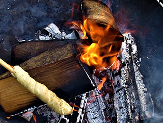 Ein Stockbrot wird über dem Feuer gebacken.